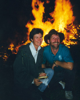 juli and larry posing in front of a bonfire