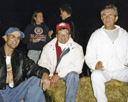 three men sitting on a hay bale